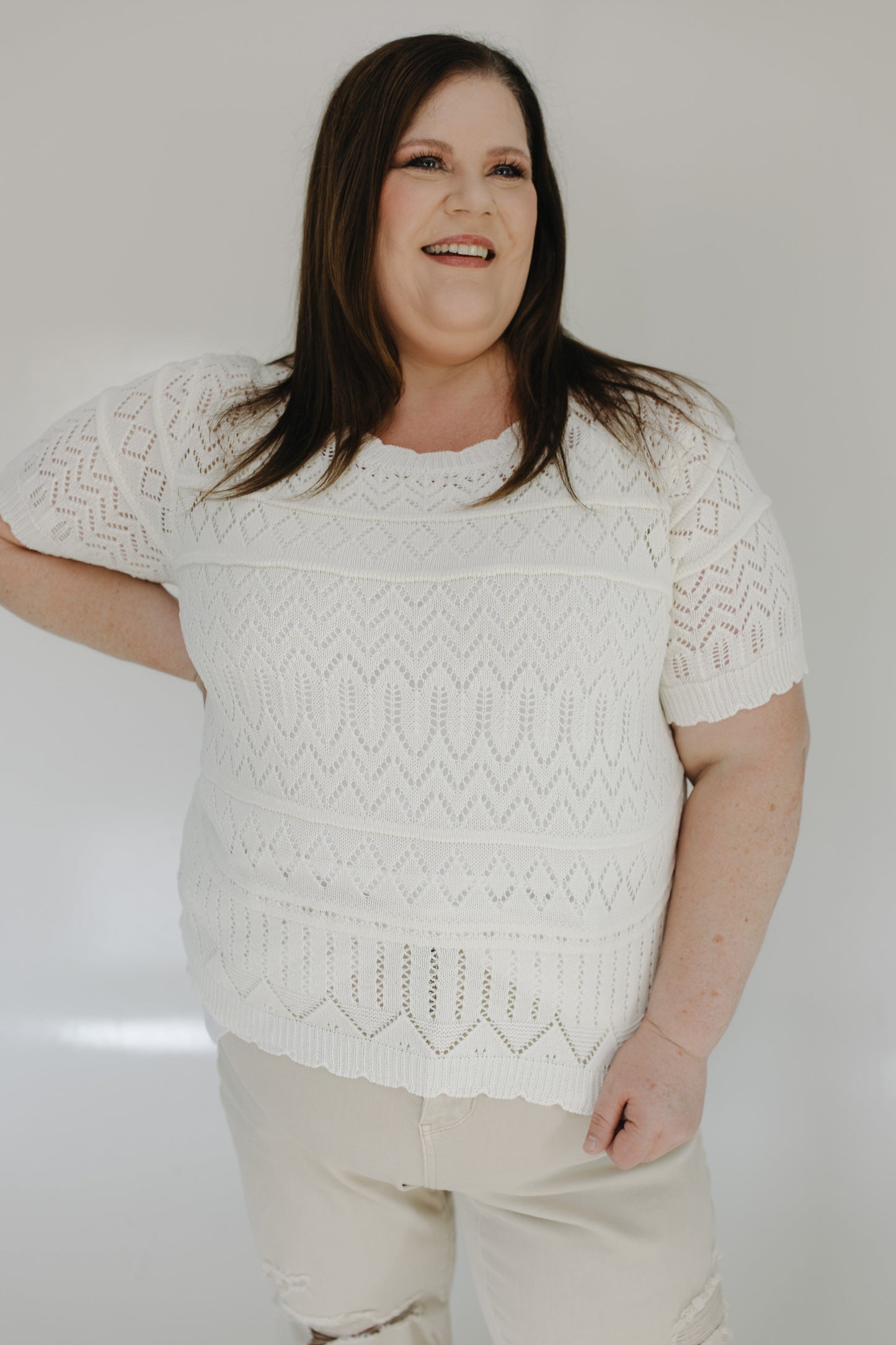 Woman wearing a white patterned sweater against a plain background