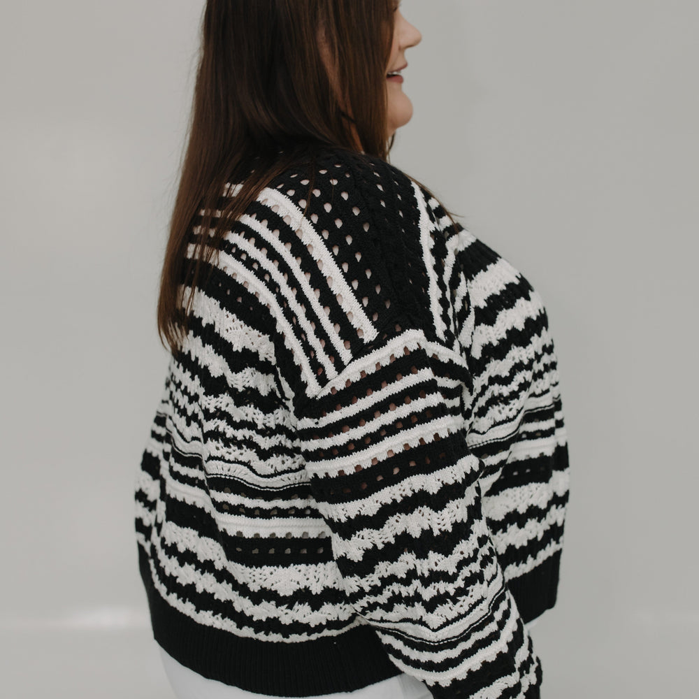 Person wearing a black and white striped sweater against a plain background