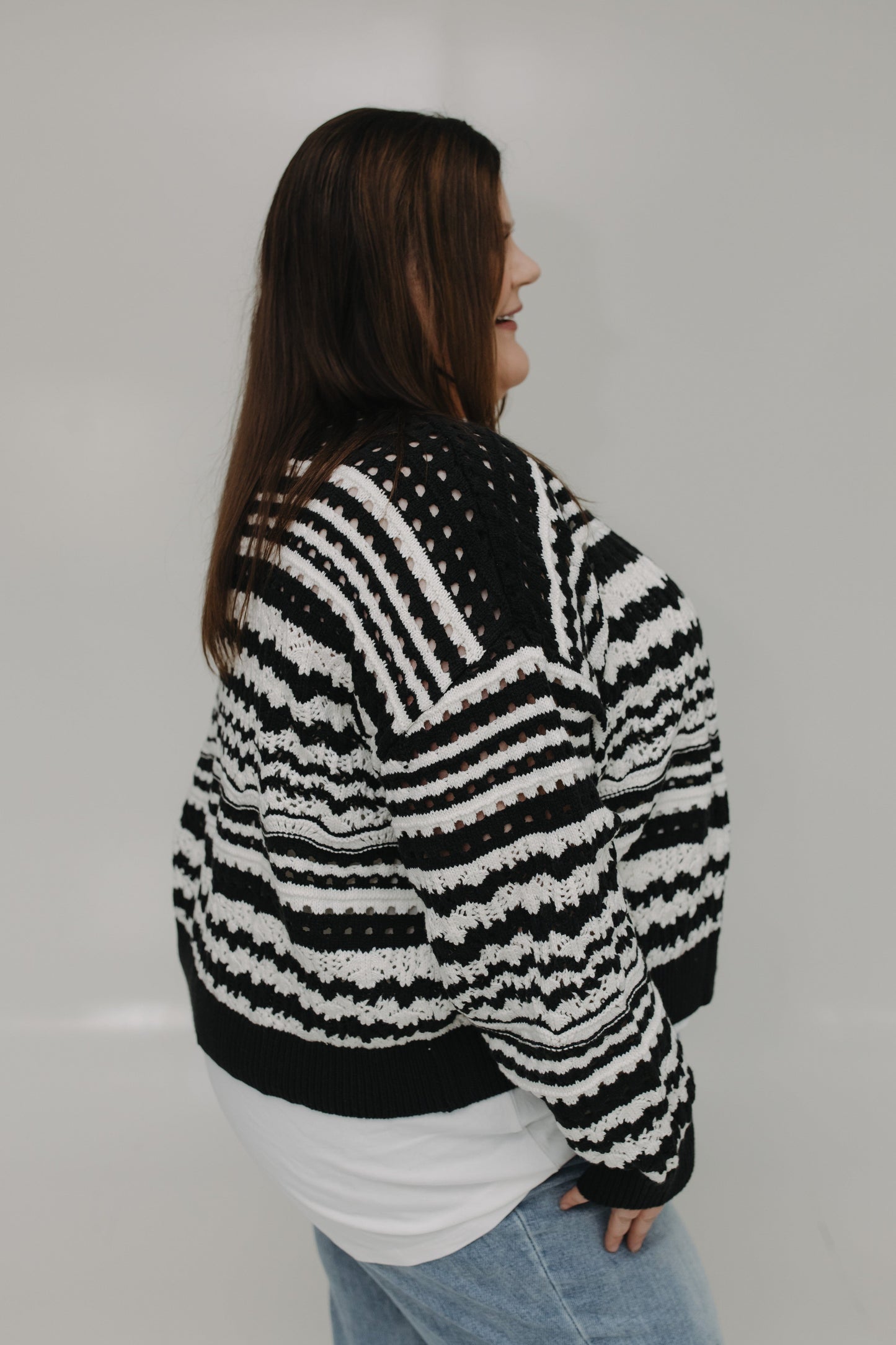 Person wearing a black and white striped sweater against a plain background