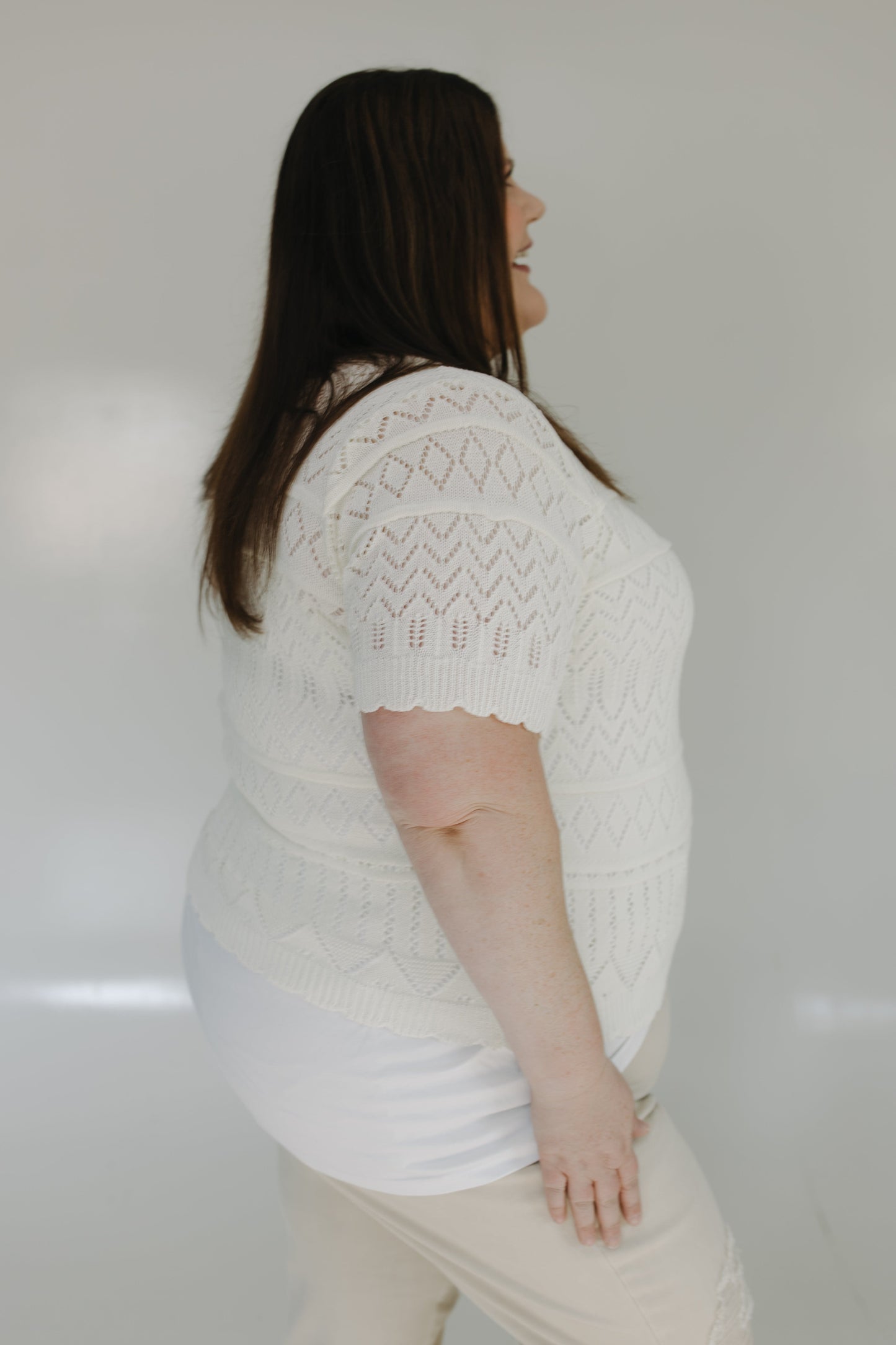 Woman wearing a white knit sweater against a plain background