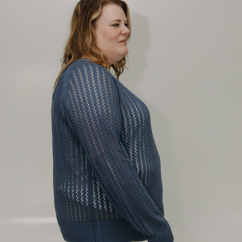 Person wearing a blue knitted sweater against a plain background