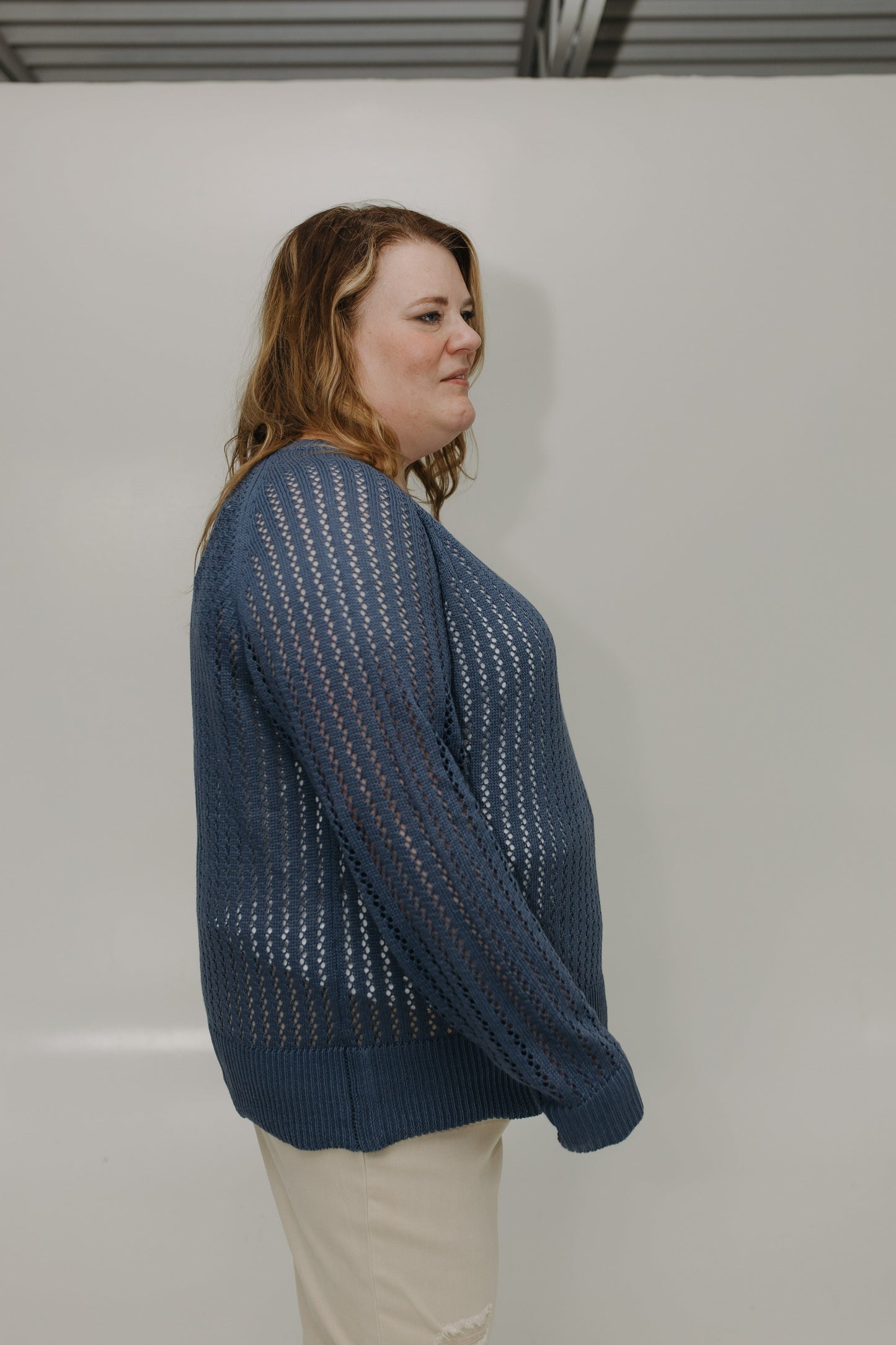 Person wearing a blue knitted sweater against a plain background
