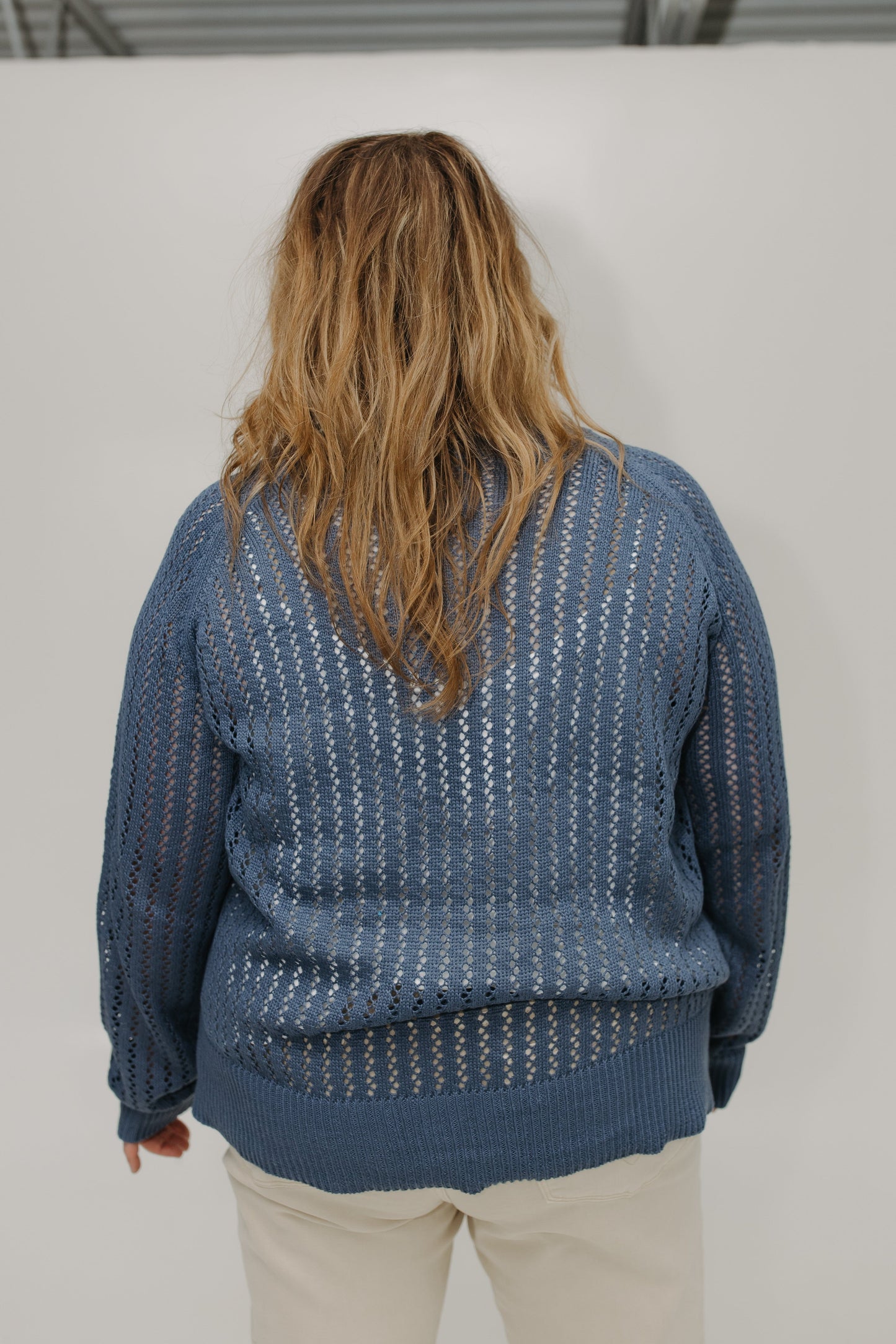 Person wearing a blue patterned sweater from behind on a plain background