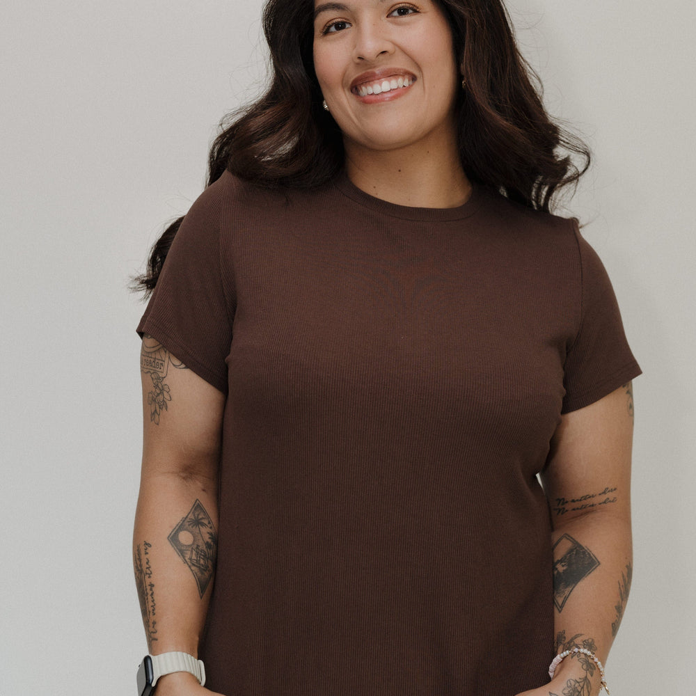 Woman wearing a brown t-shirt against a plain background