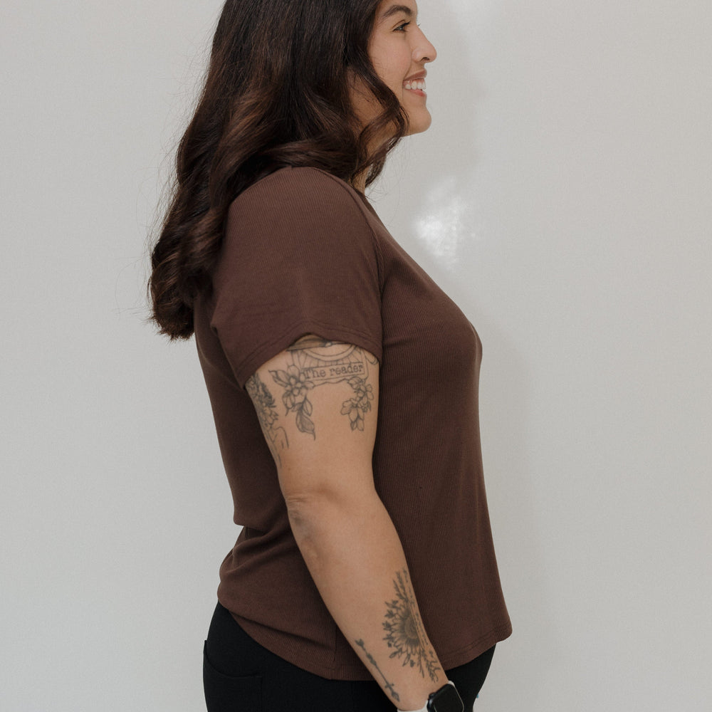 Woman wearing a brown t-shirt against a plain background