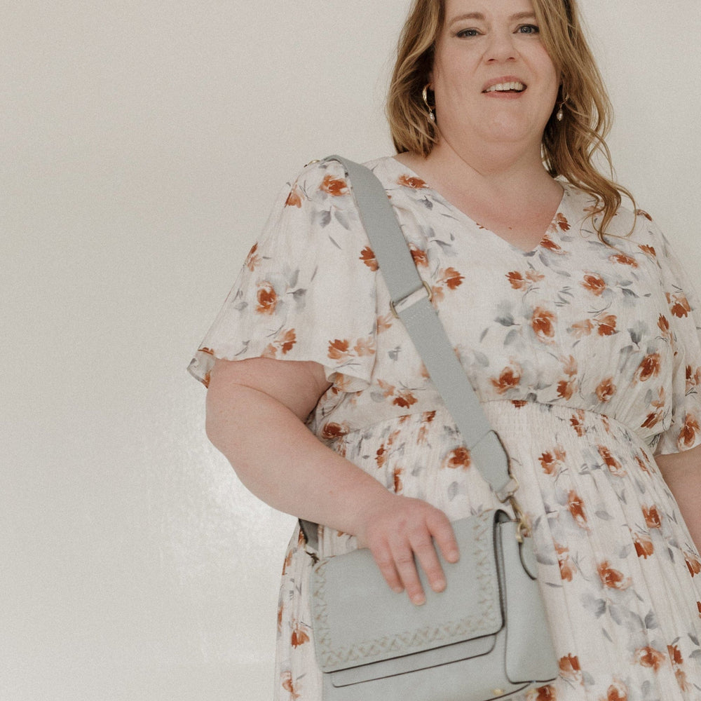 This stylish handbag features a vegan faux leather construction with a dusty blue finish. The flap-over top is secured with a strong magnetic closure, plus an added back zipper pocket for extra storage. Whipstitch detail adds a touch of texture, while the adjustable and removable shoulder strap allows for easy portability