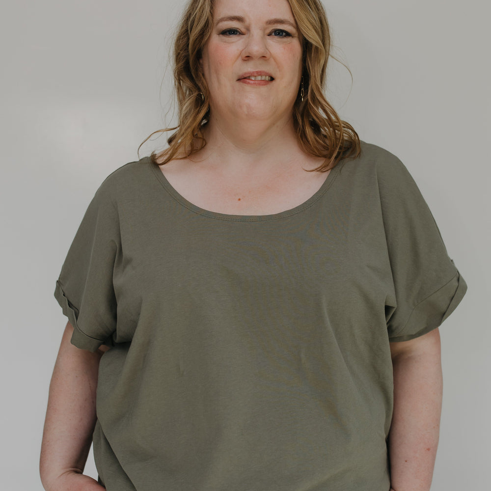 Woman wearing an olive green outfit against a plain background