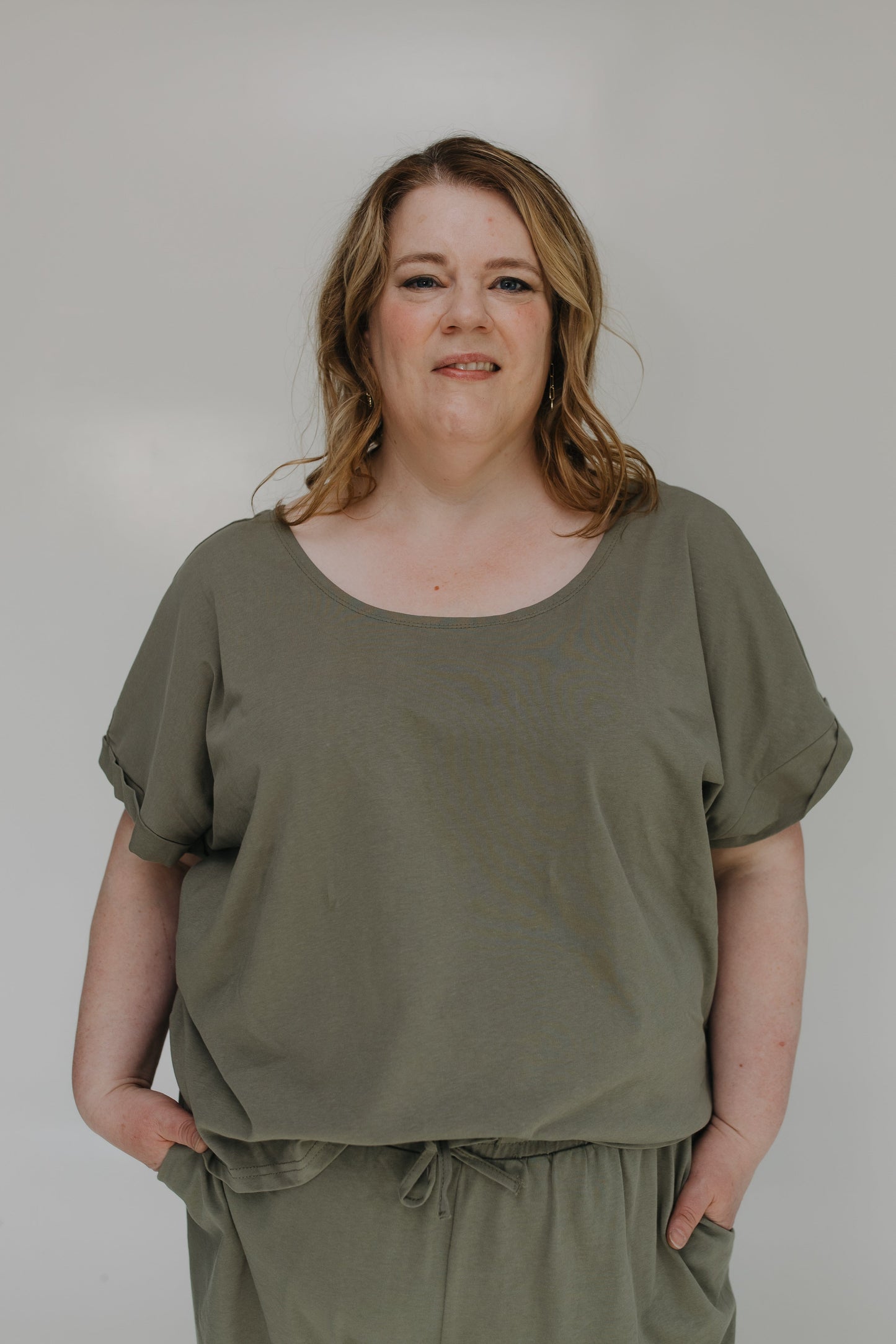 Woman wearing an olive green outfit against a plain background