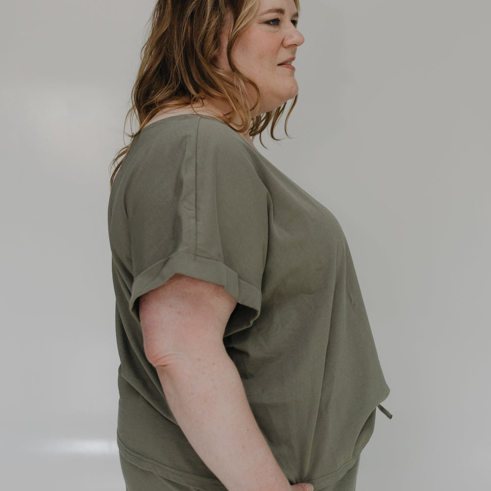 Woman wearing an olive green set against a plain background