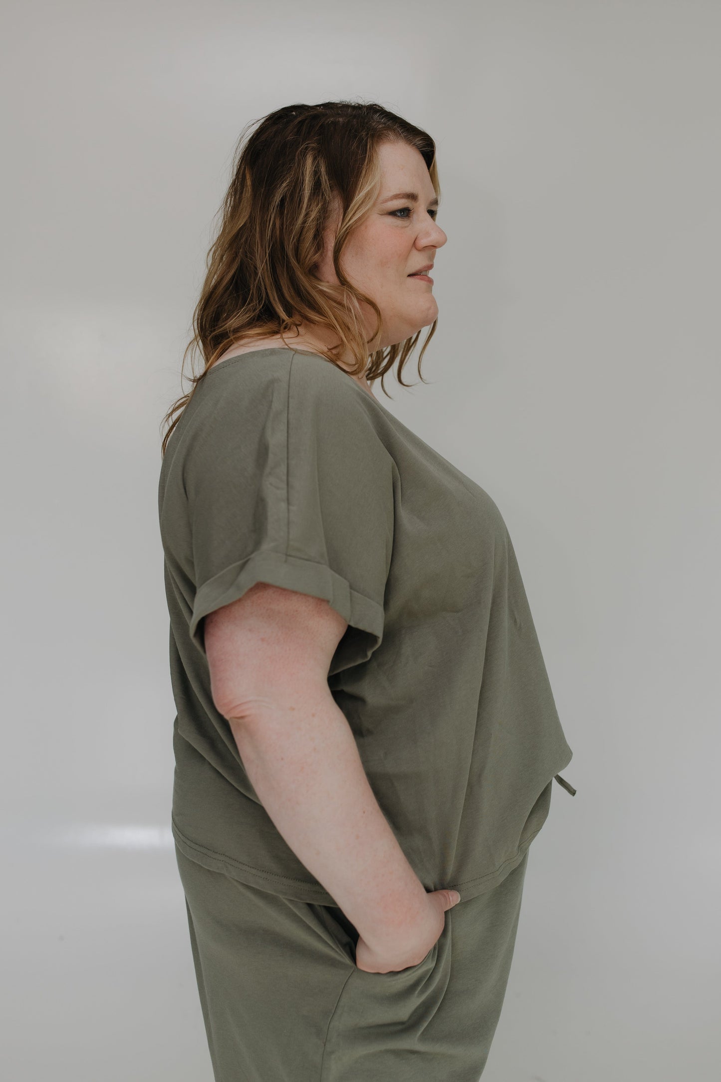 Woman wearing an olive green set against a plain background