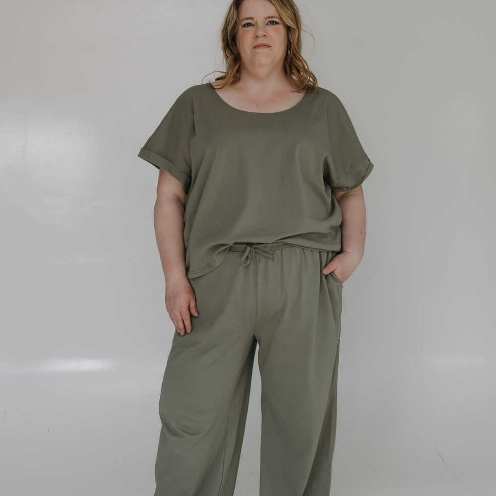 Person wearing a green top and pants set against a white background