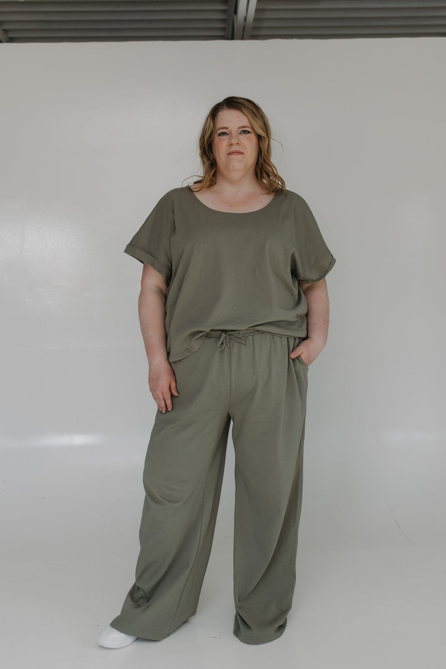 Person wearing a green top and pants set against a white background
