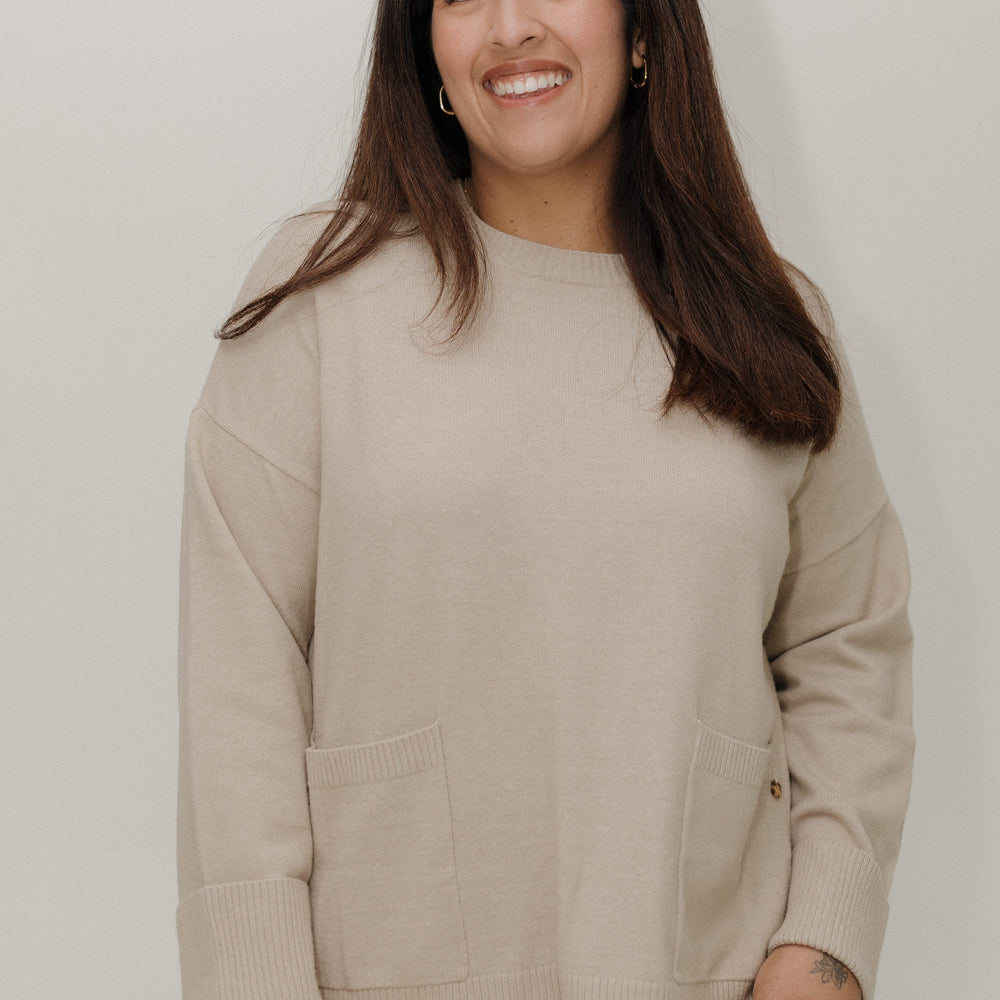 Woman wearing a beige sweater against a plain background