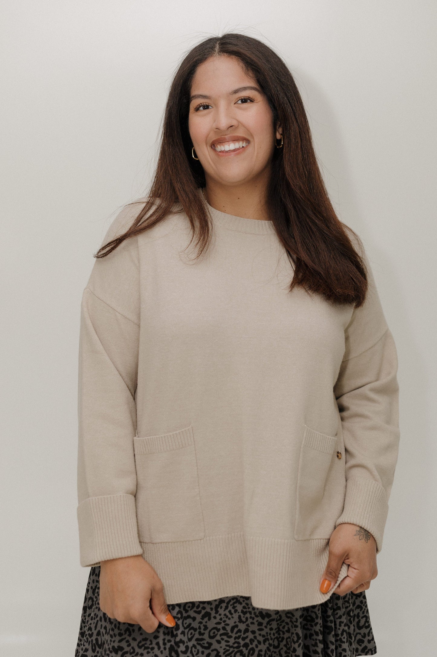 Woman wearing a beige sweater against a plain background