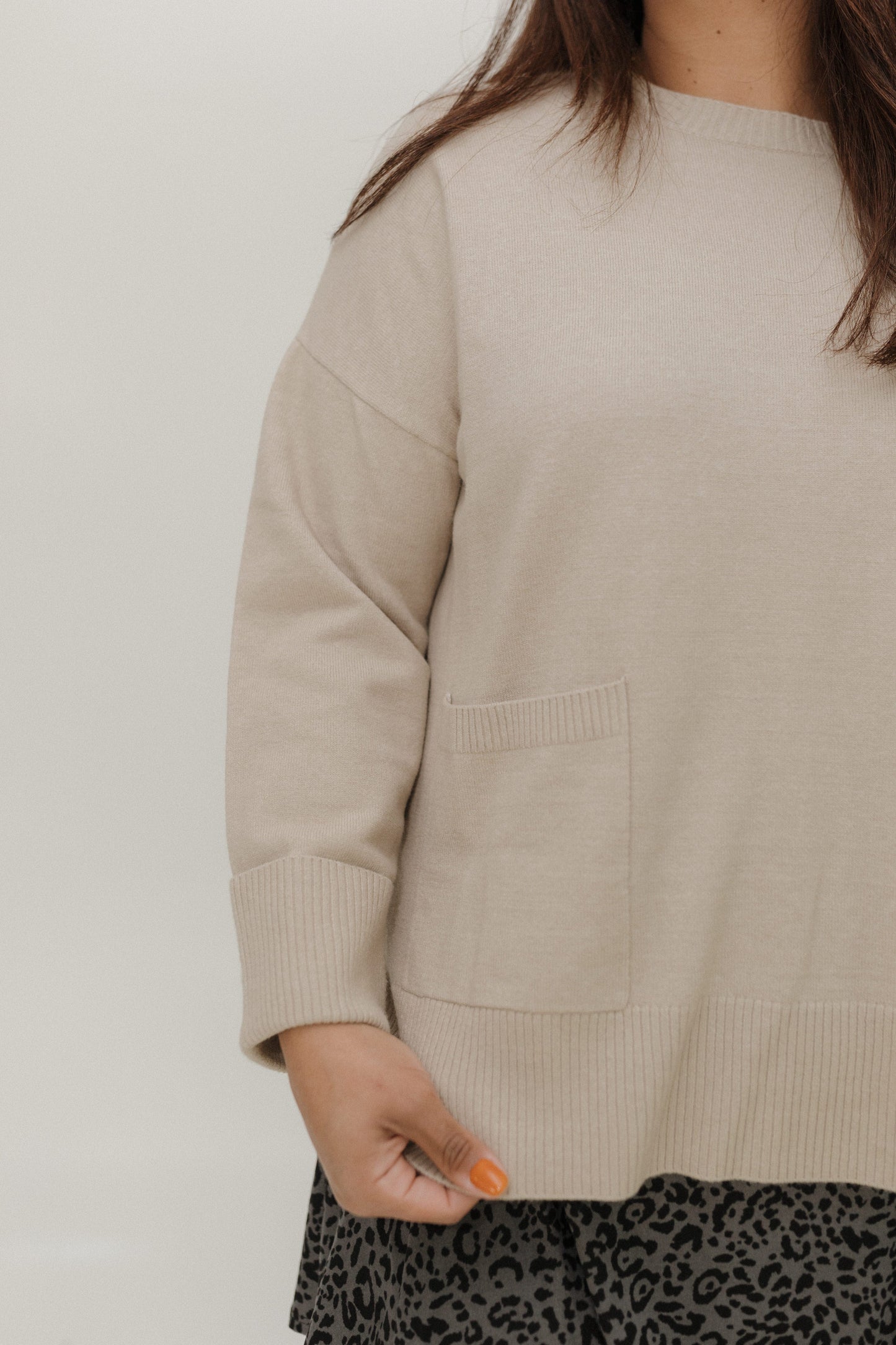 Beige sweater worn by a person on a plain background