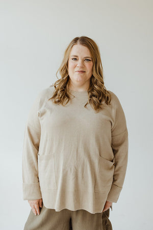 A person with long hair wears the CUFFED SWEATER WITH POCKETS by Yesta, showcasing its classic ribbed crew neckline, as they stand against a plain background.