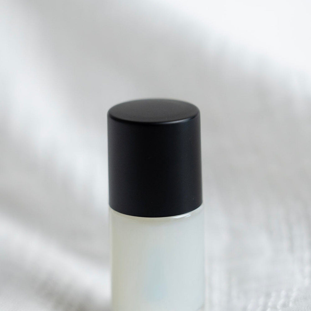 Small white bottle with a black cap on a textured white background