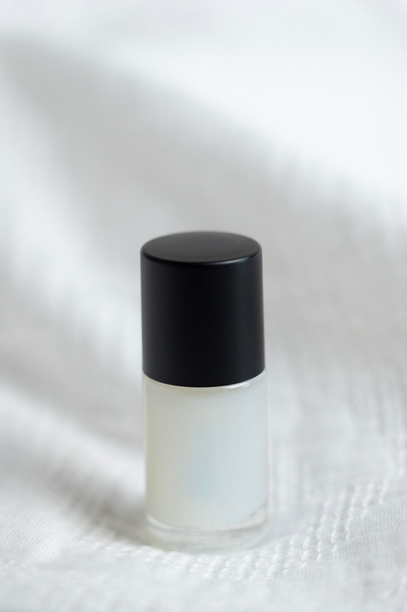 Small white bottle with a black cap on a textured white background