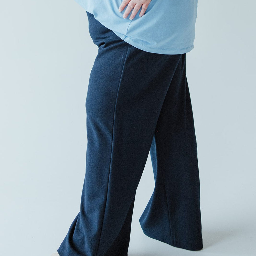 A person is wearing a light blue top and dark blue dress pants with wide legs, standing on a light background. The outfit features lightweight fabric that adds comfort and elegance to the look.