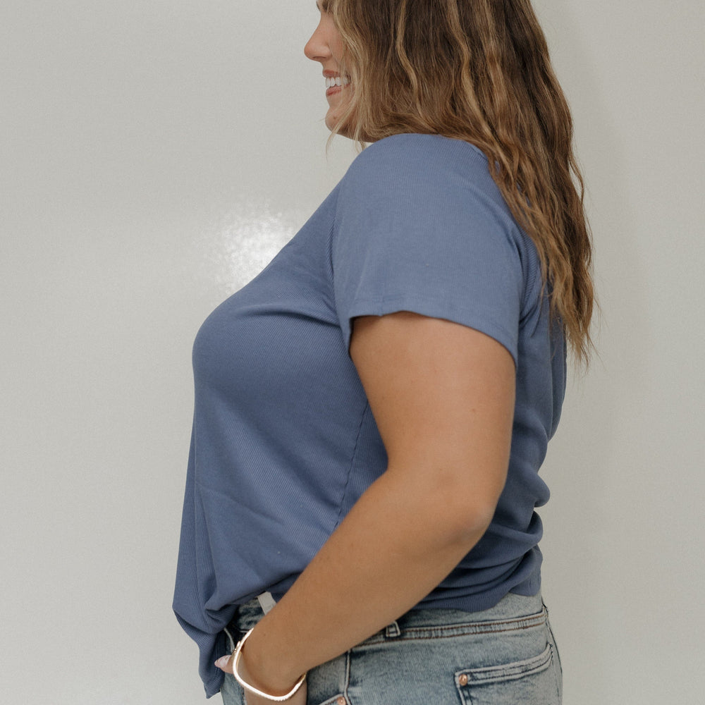 Woman wearing a blue t-shirt and jeans against a plain background