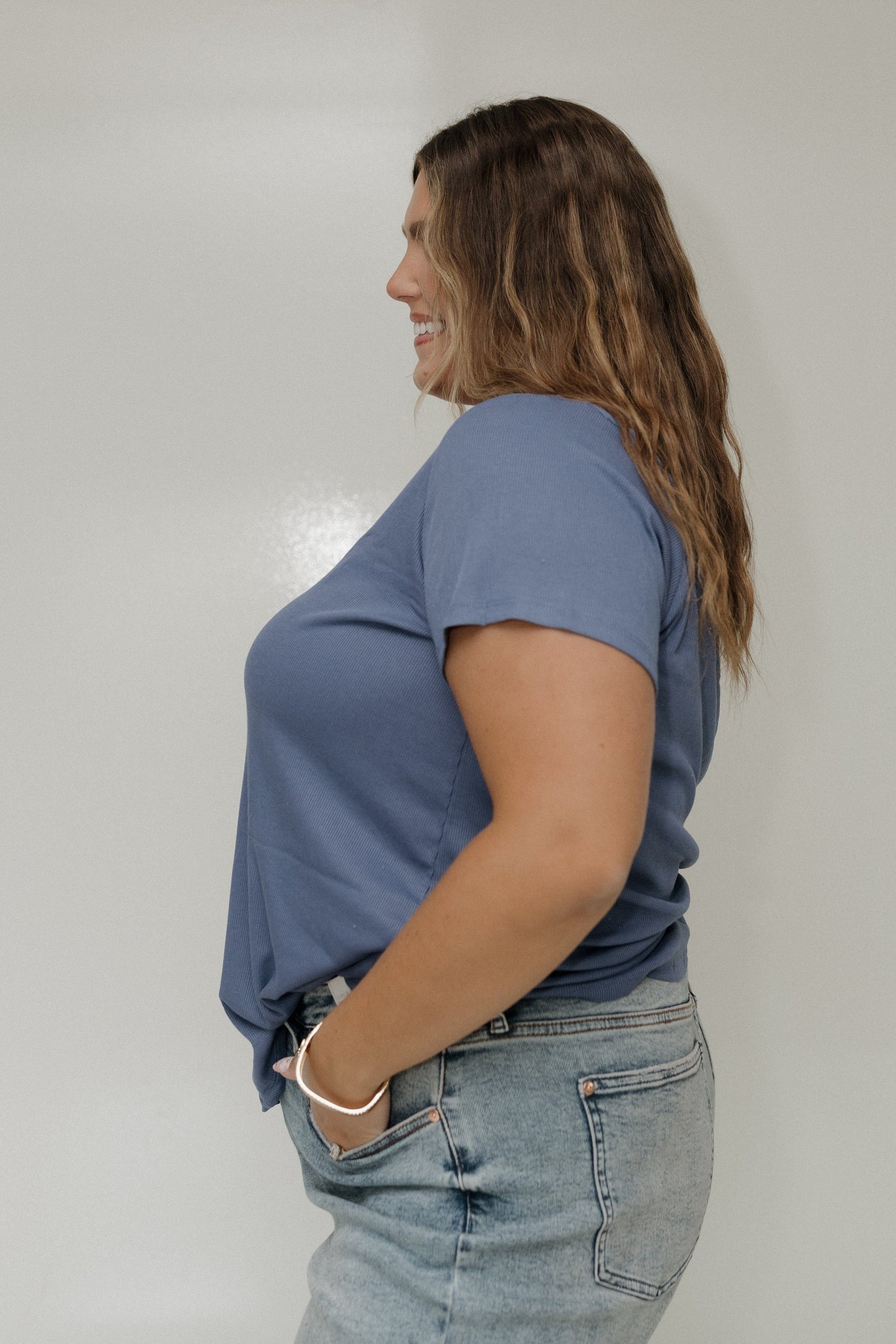 Woman wearing a blue t-shirt and jeans against a plain background