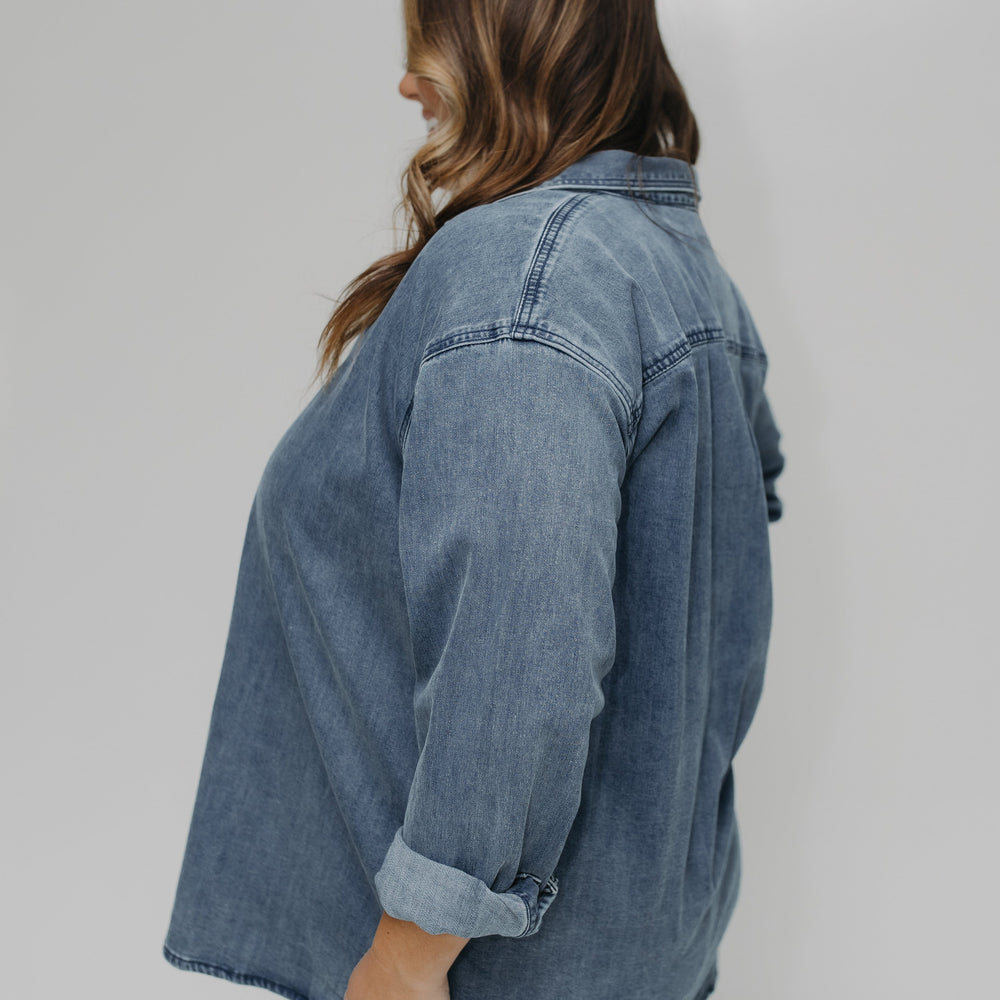 Person wearing a denim jacket against a plain background