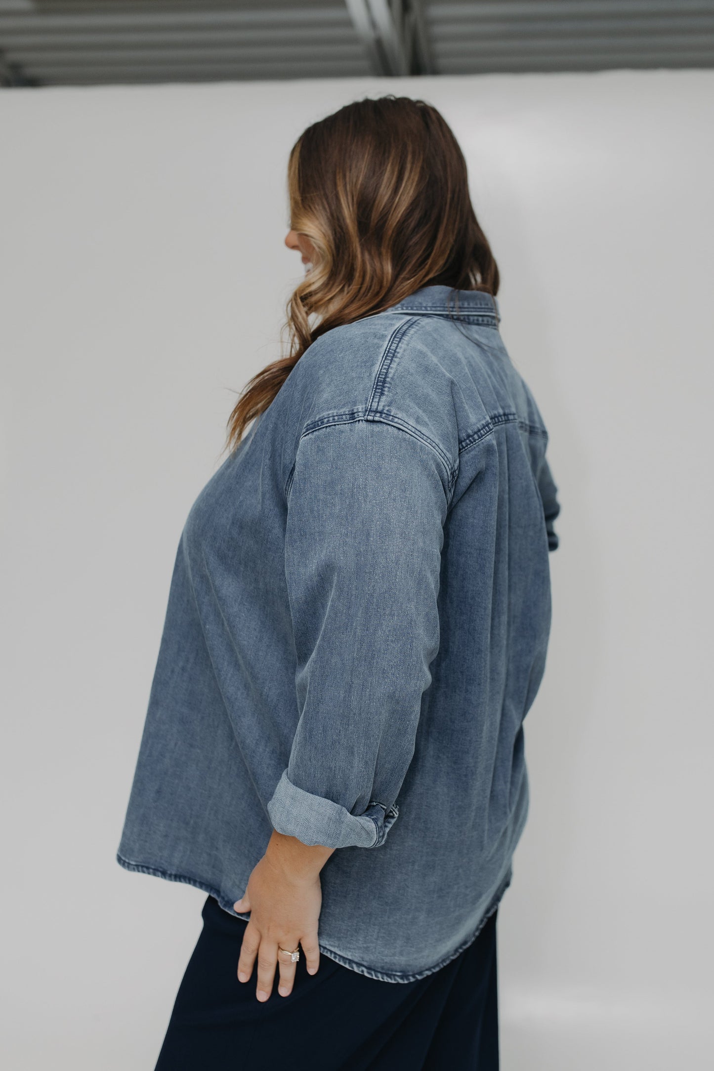 Person wearing a denim jacket against a plain background