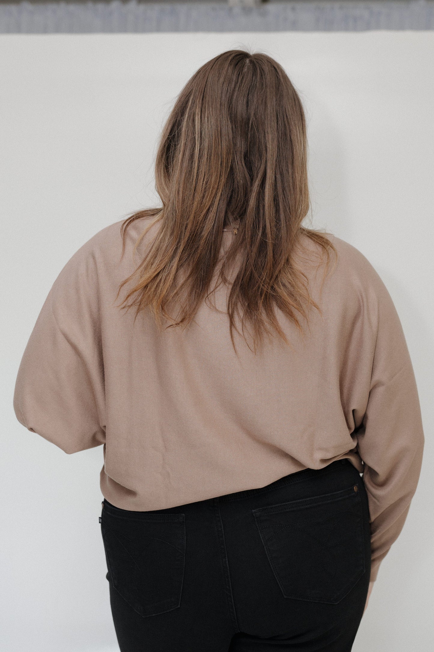 Person wearing a beige shirt and black pants against a white background