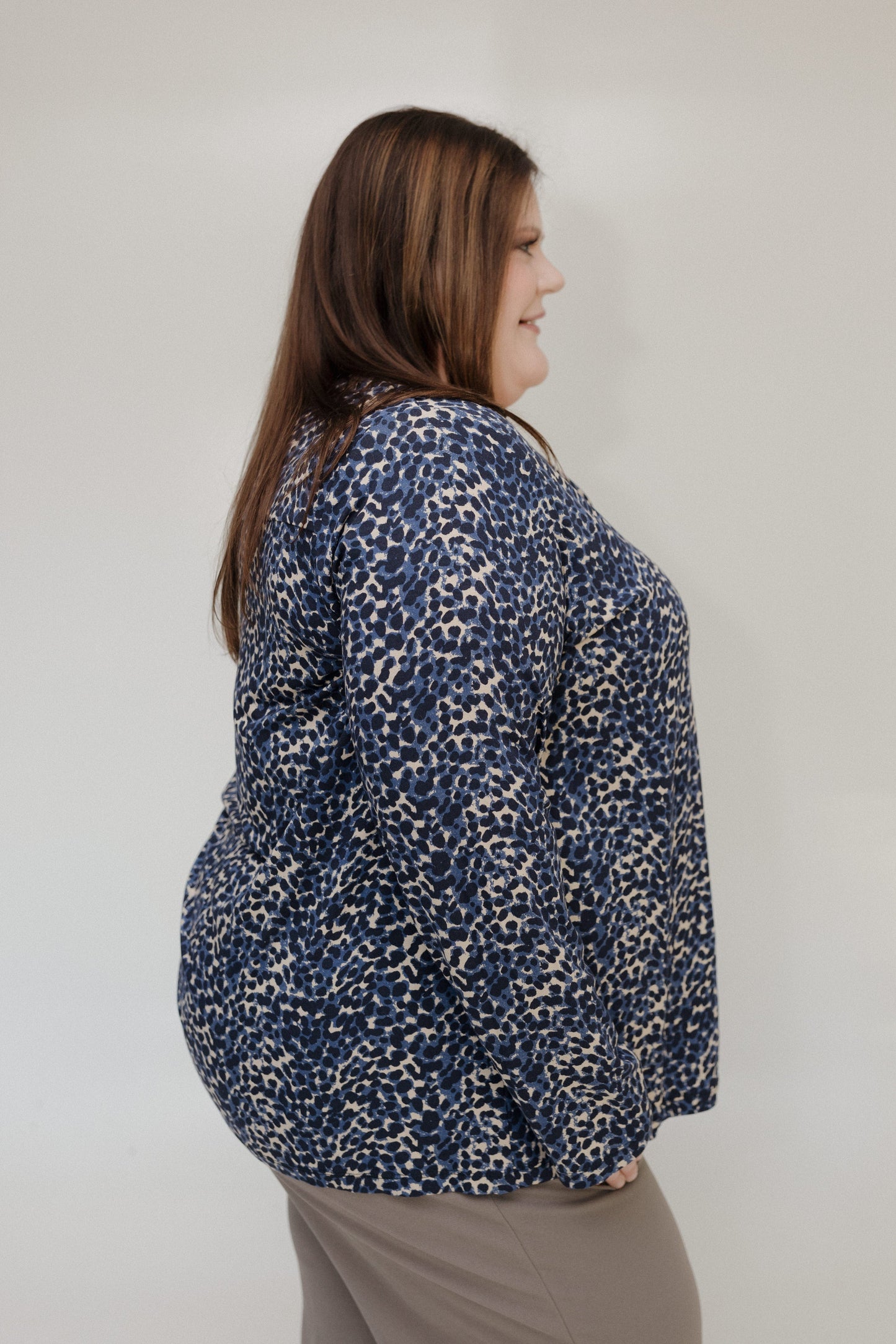 Woman wearing a blue patterned blouse against a plain background