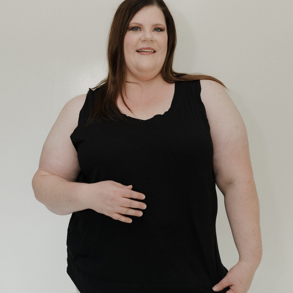 Woman wearing a black sleeveless top against a plain background