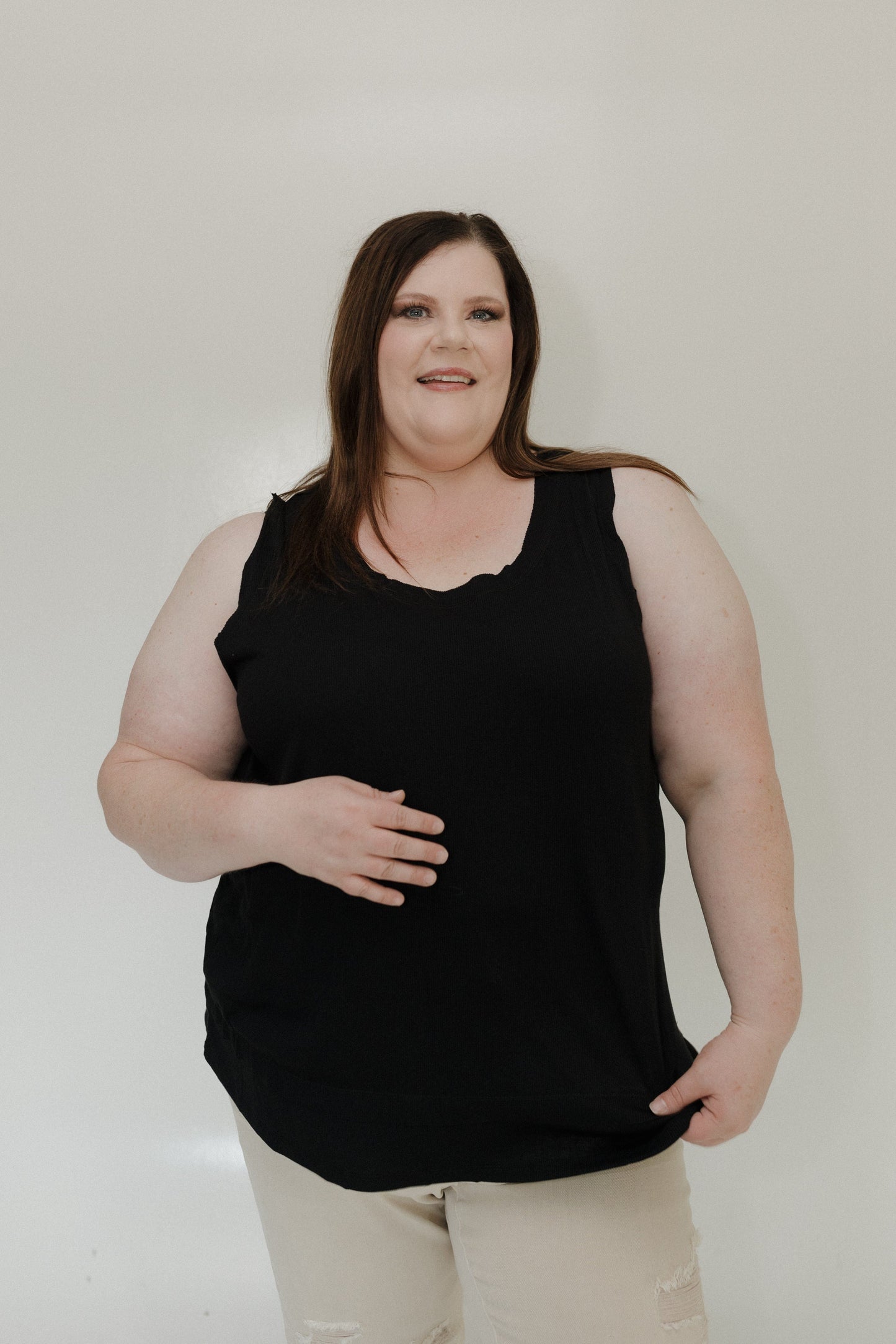Woman wearing a black sleeveless top against a plain background