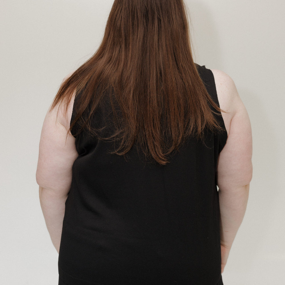 Person wearing a black sleeveless top against a plain background