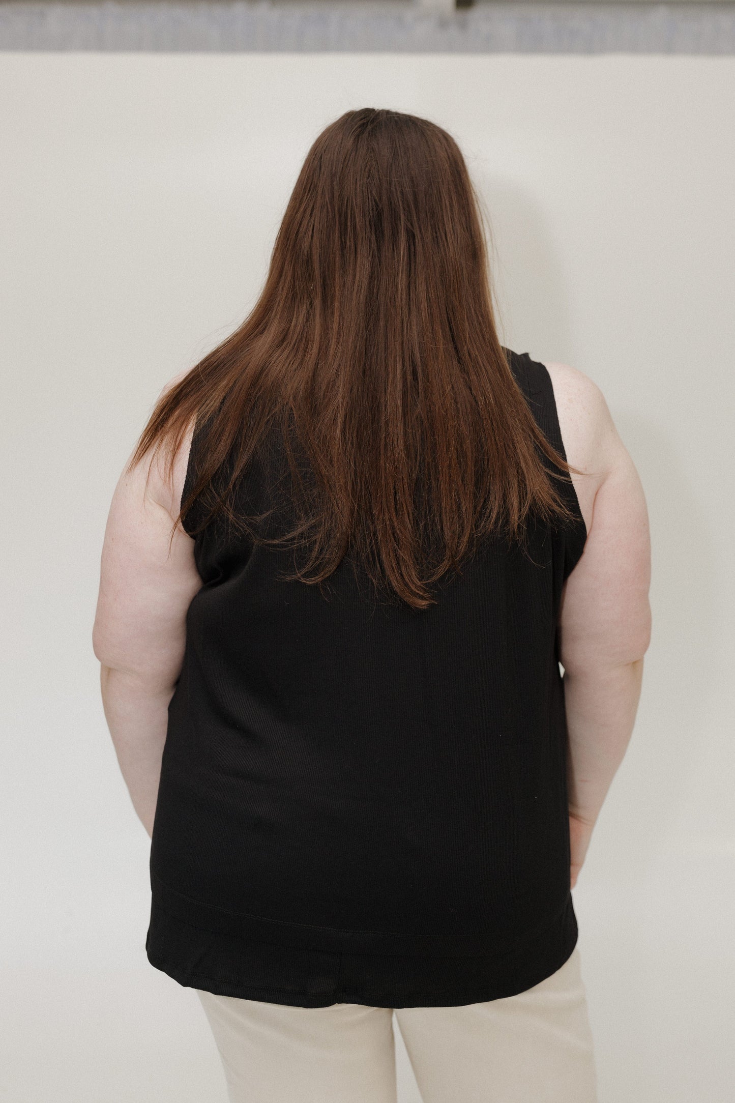 Person wearing a black sleeveless top against a plain background