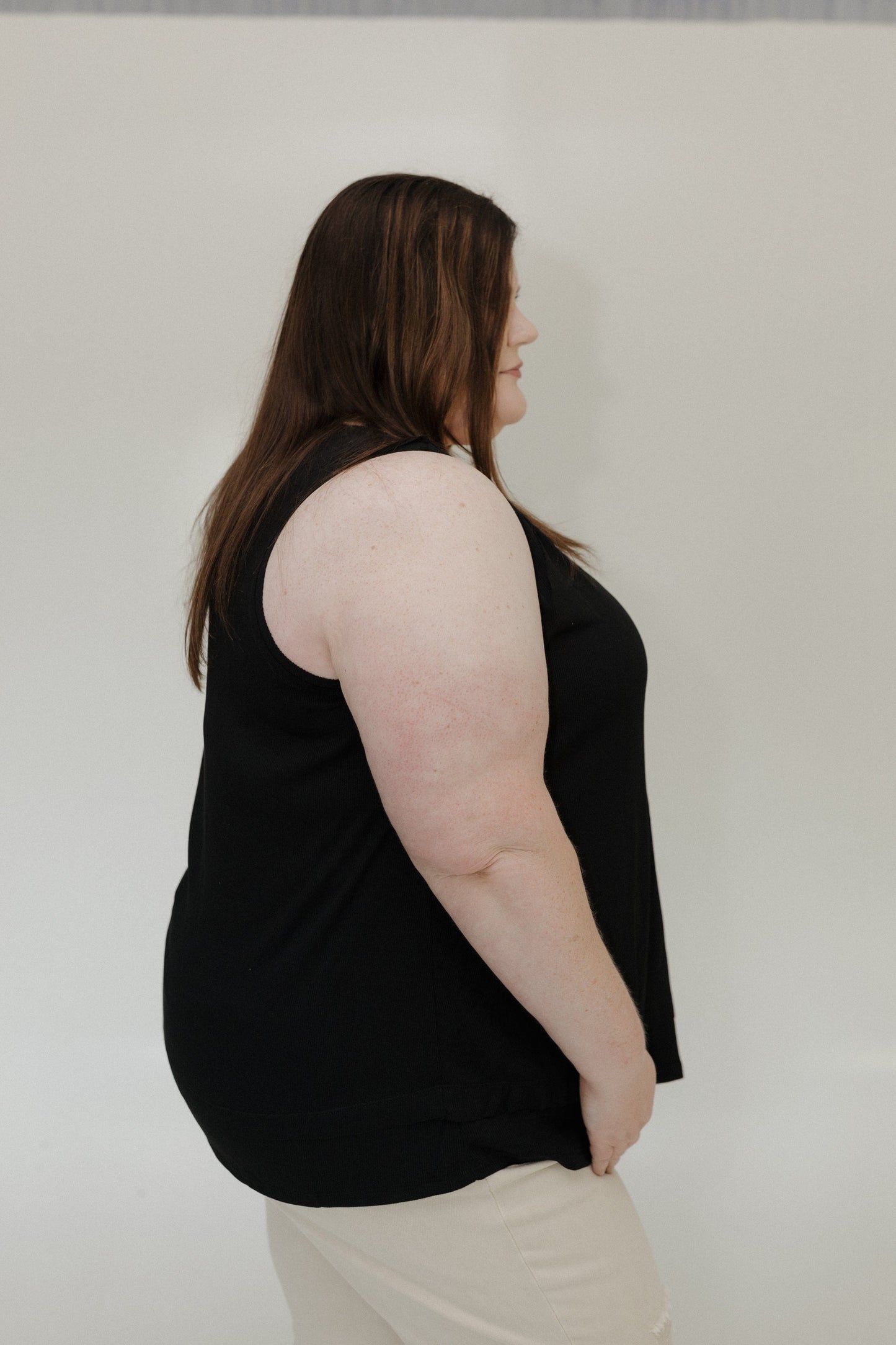 Person wearing a black sleeveless top against a plain background