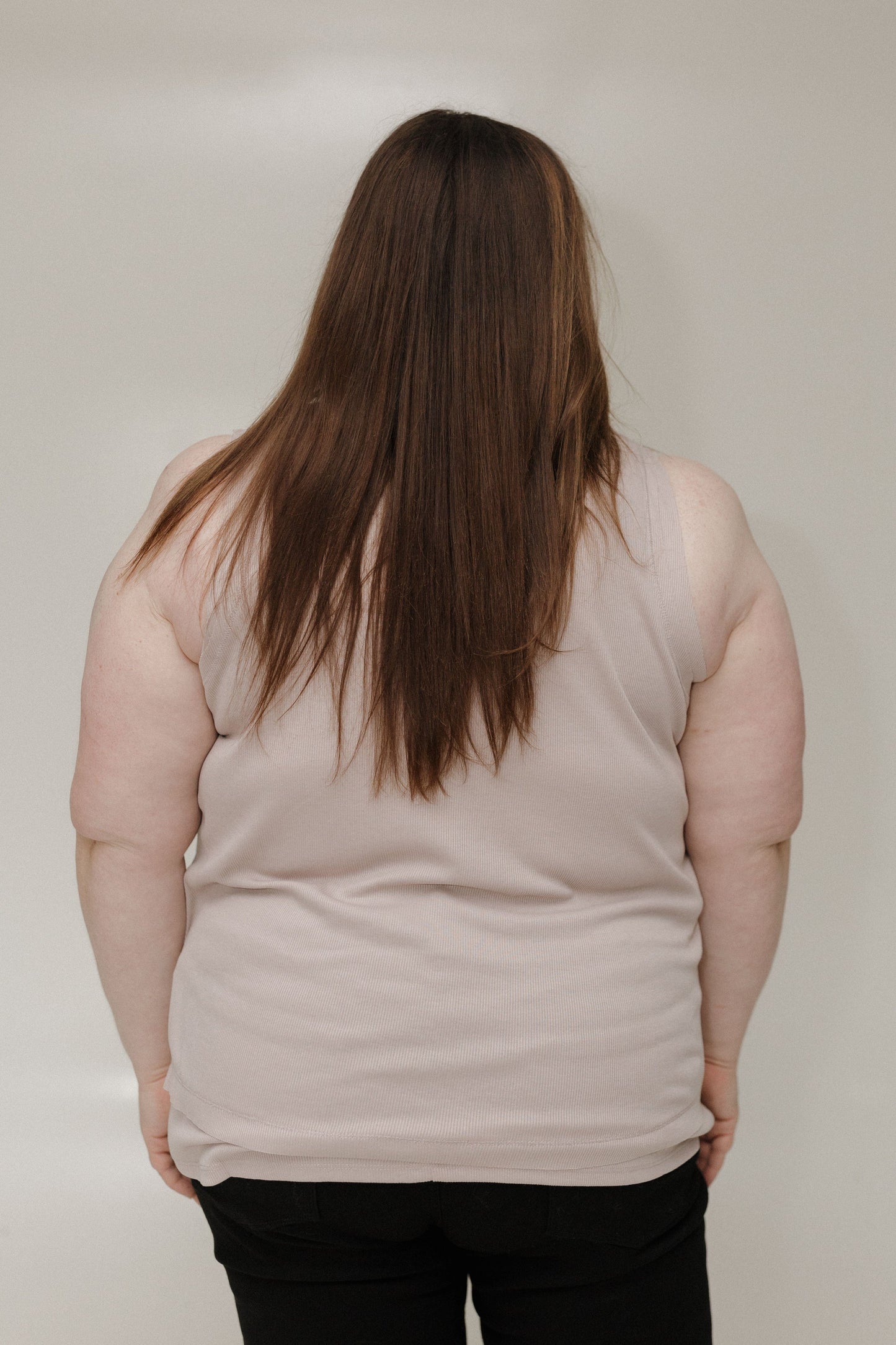 Person wearing a beige sleeveless top against a plain background