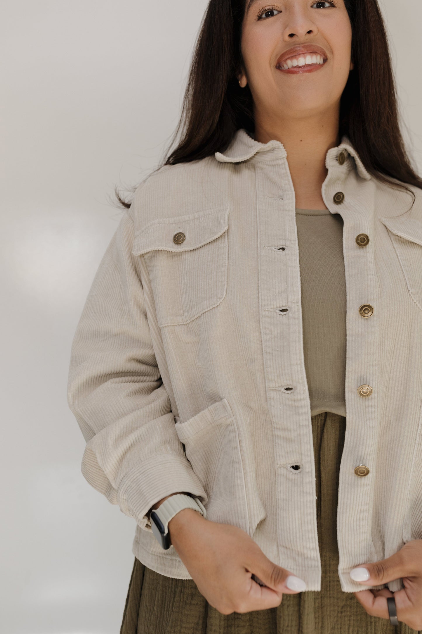 Woman wearing a beige jacket with a plain background