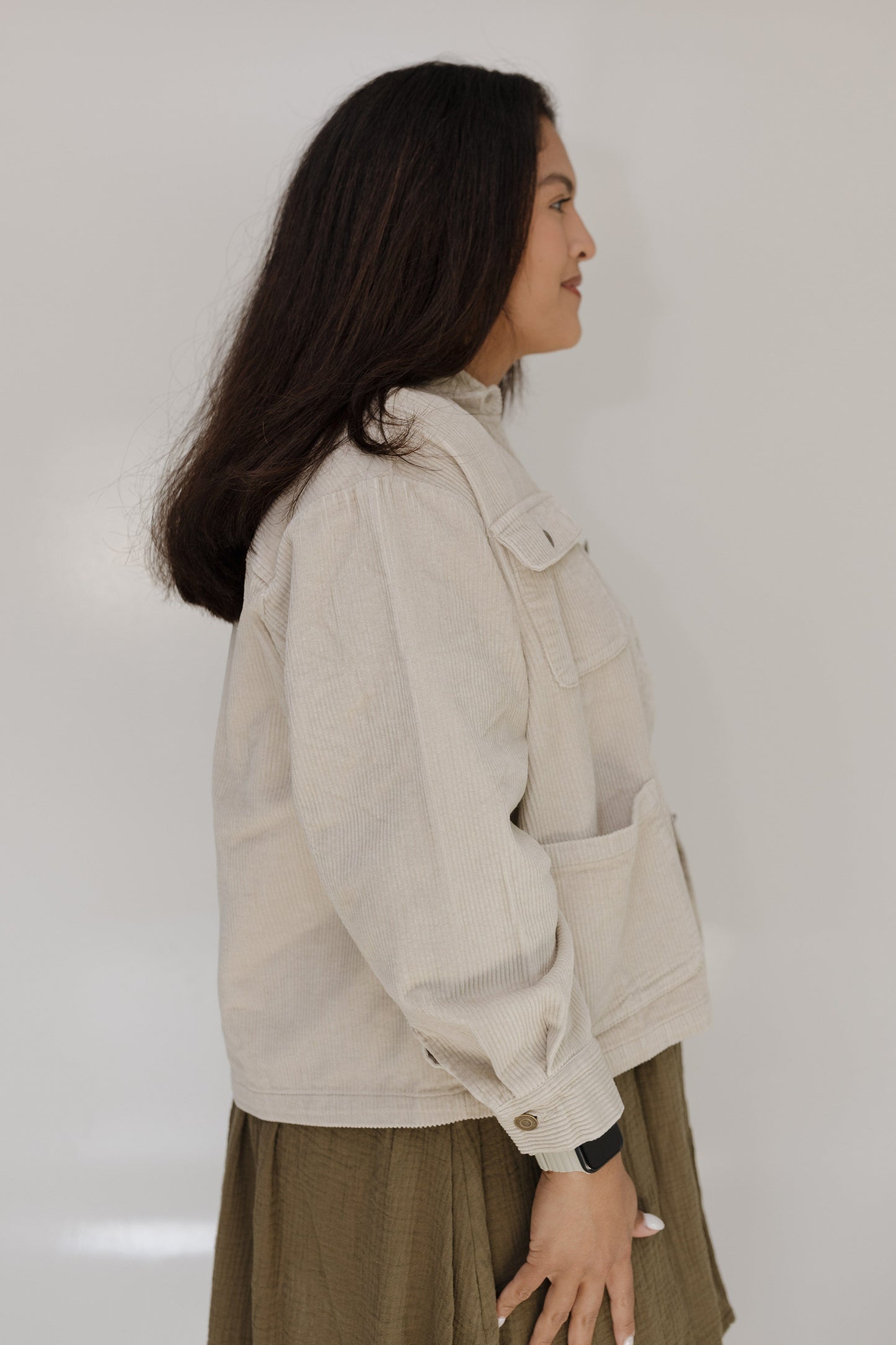 Woman wearing a beige jacket against a plain background