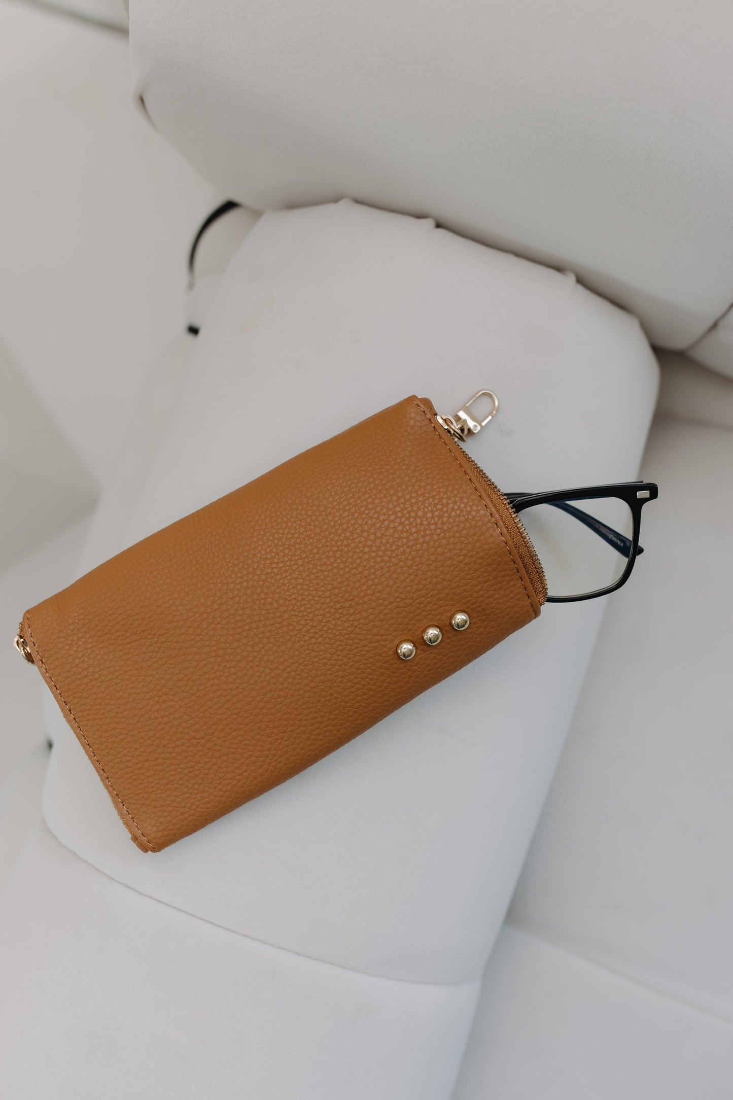 Brown leather wallet with gold accents on a white surface