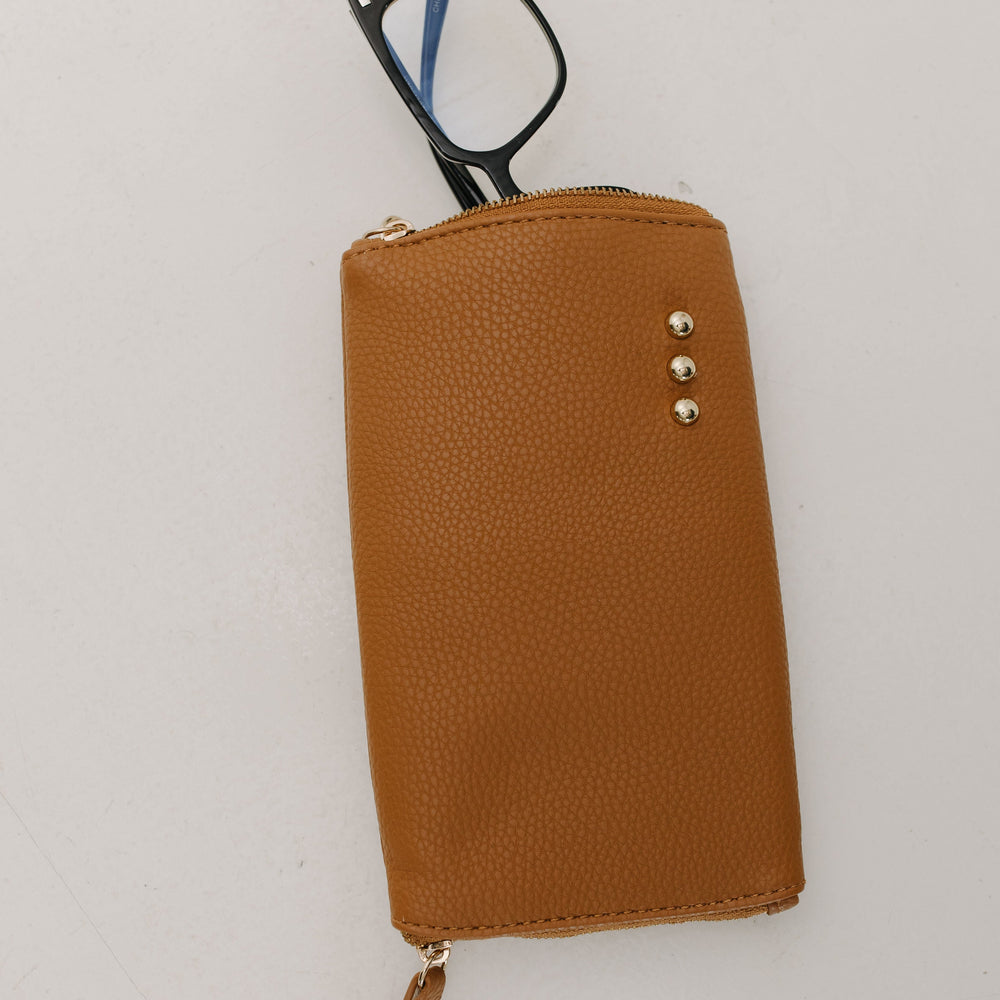Brown leather case with a zipper containing eyeglasses on a white background