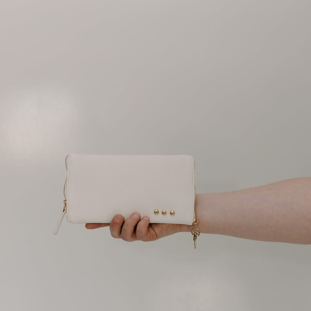 White clutch held by a hand against a plain background