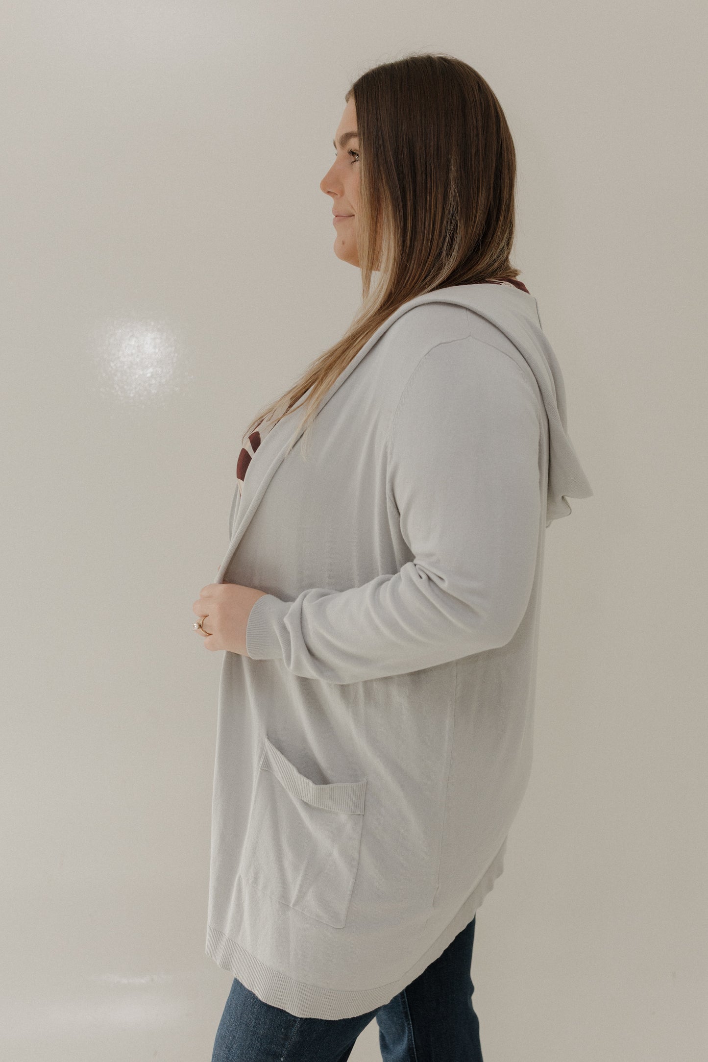 Woman wearing a light gray cardigan against a plain background