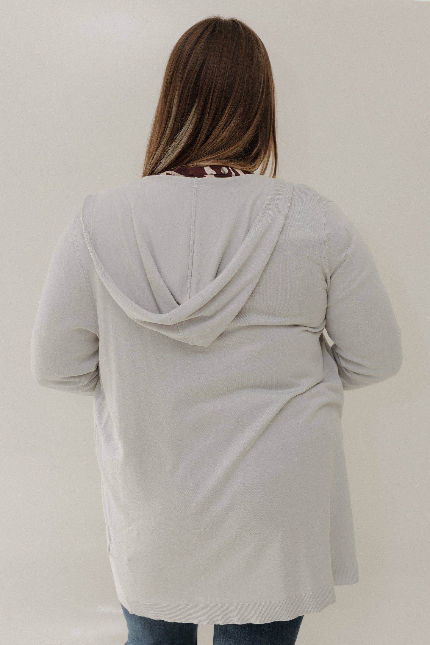 Person wearing a light gray hoodie against a plain background