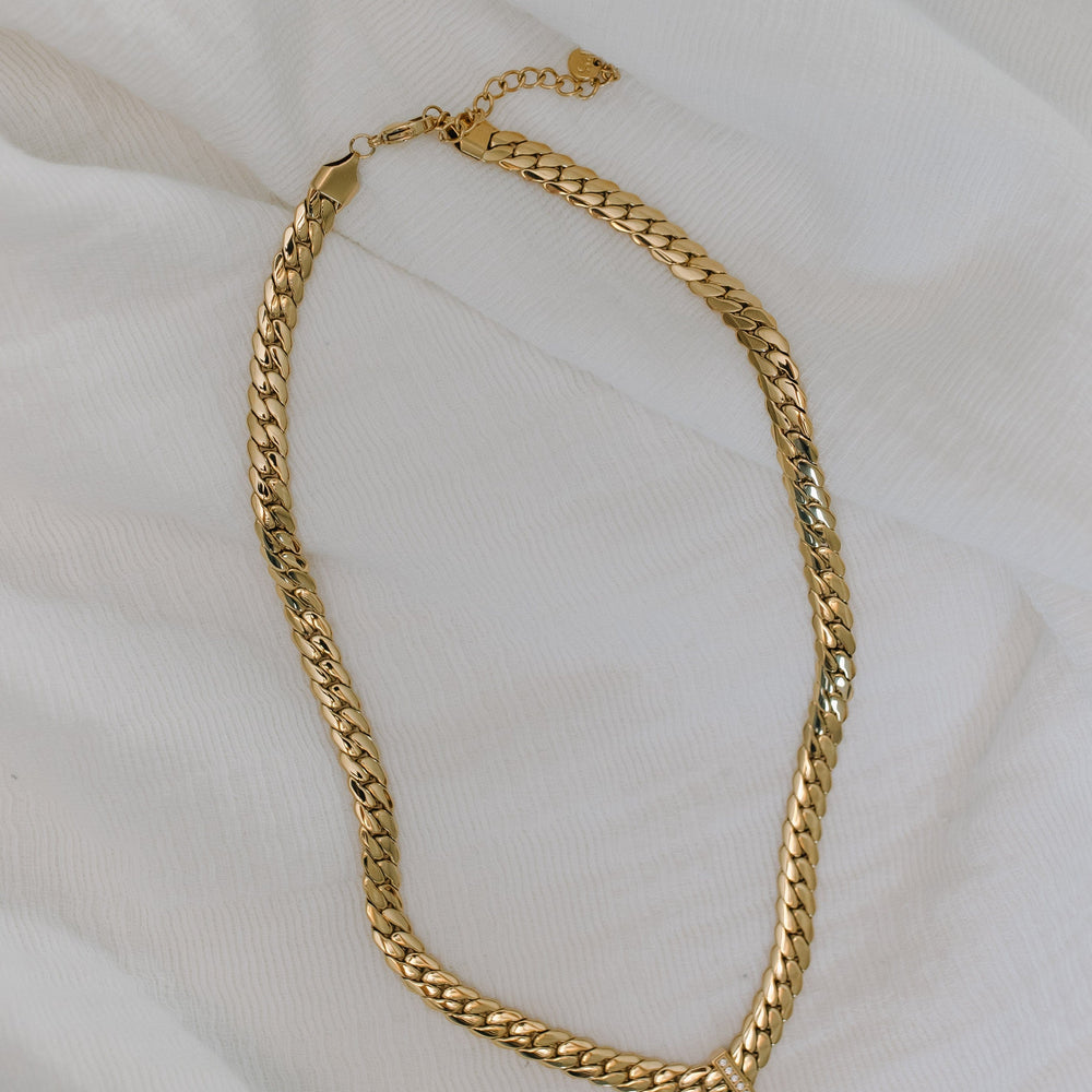 Gold chain necklace on a white fabric background