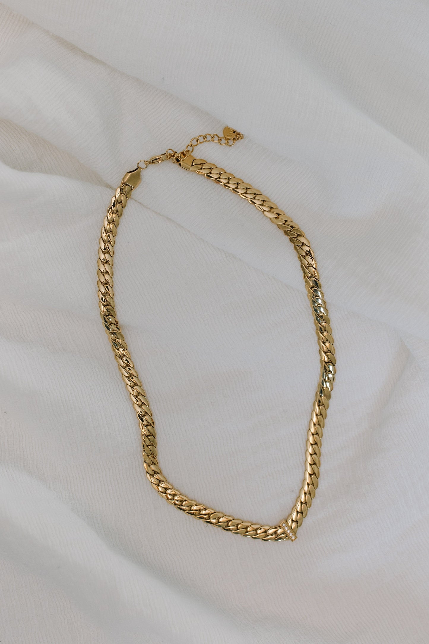 Gold chain necklace on a white fabric background