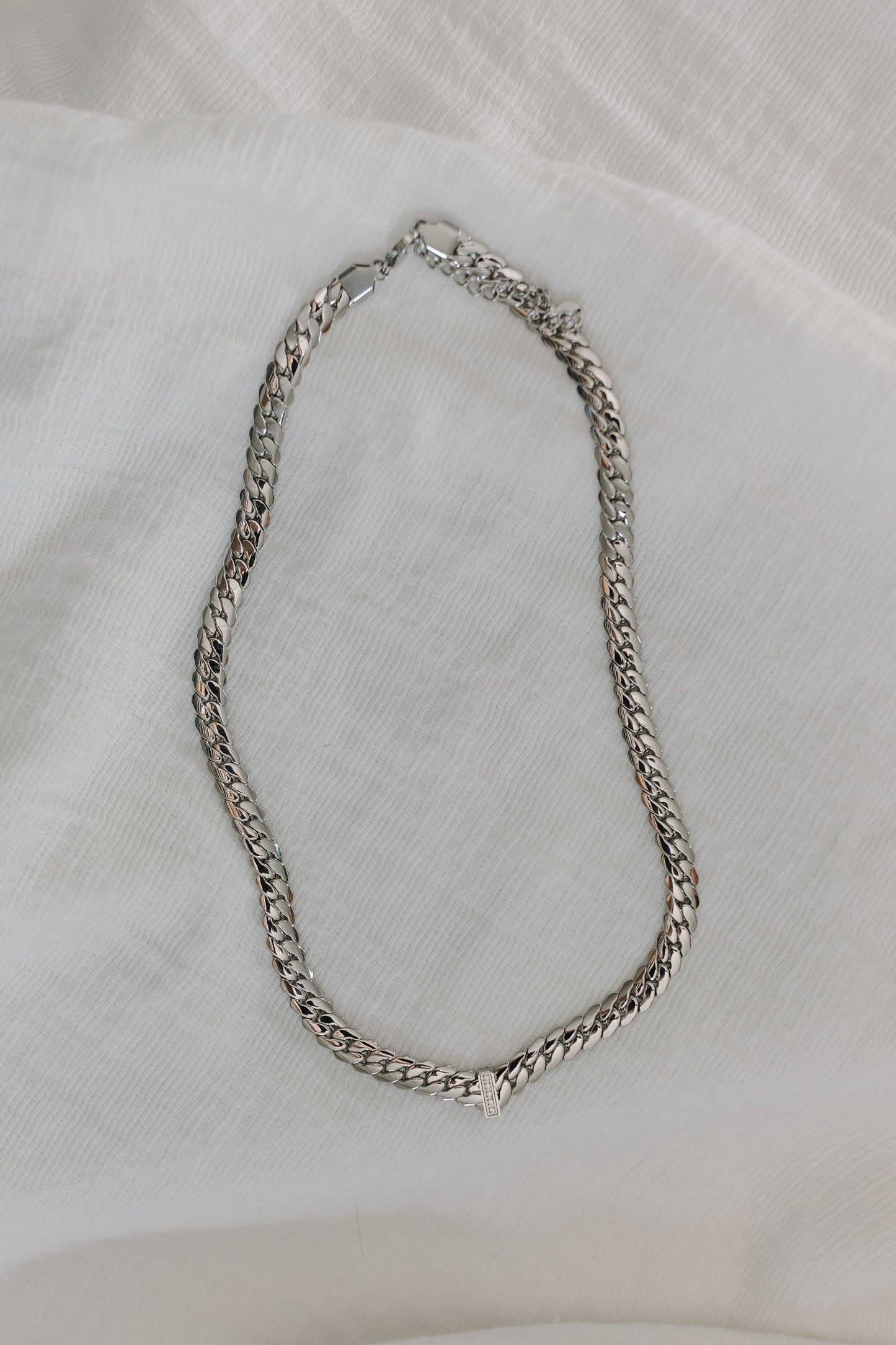 Silver chain necklace on a white fabric background