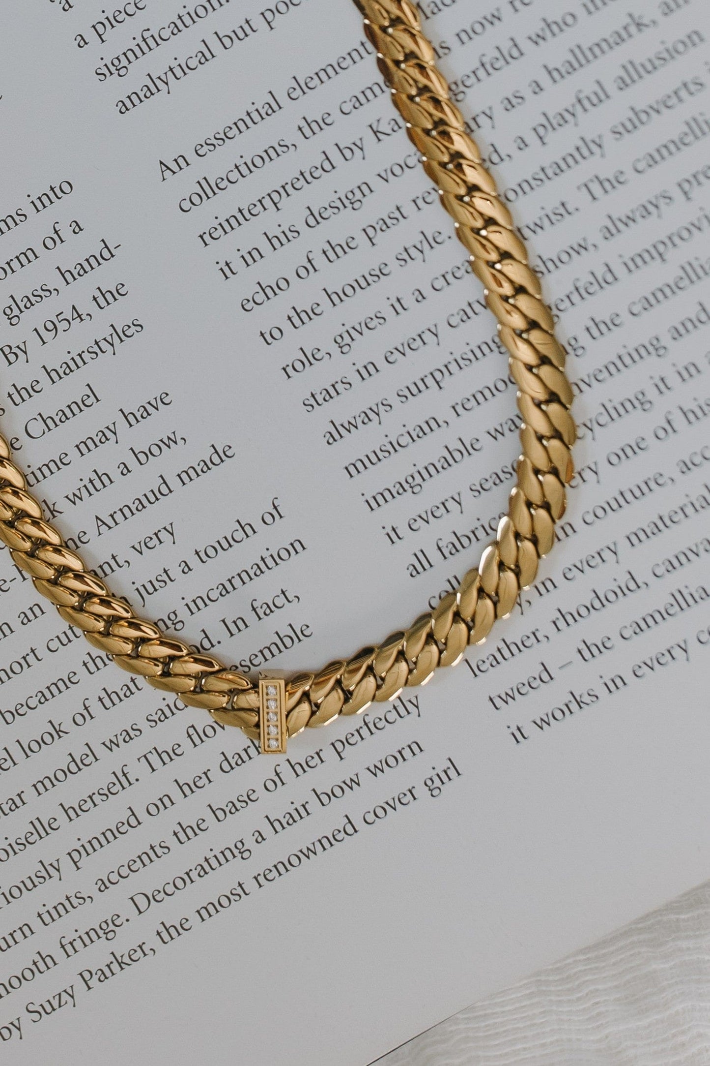 Gold chain necklace on a textured surface with text