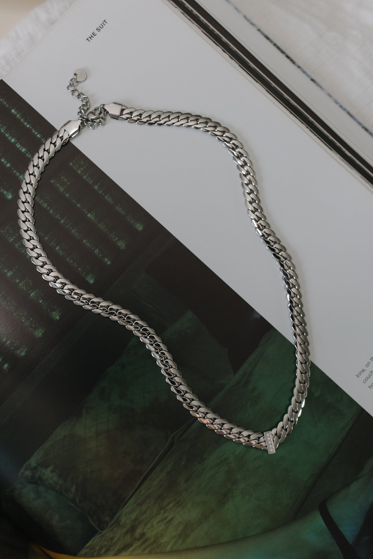 Silver chain necklace on a magazine with a blurred background