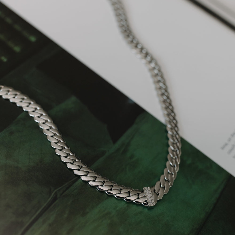 Silver chain necklace on a reflective surface