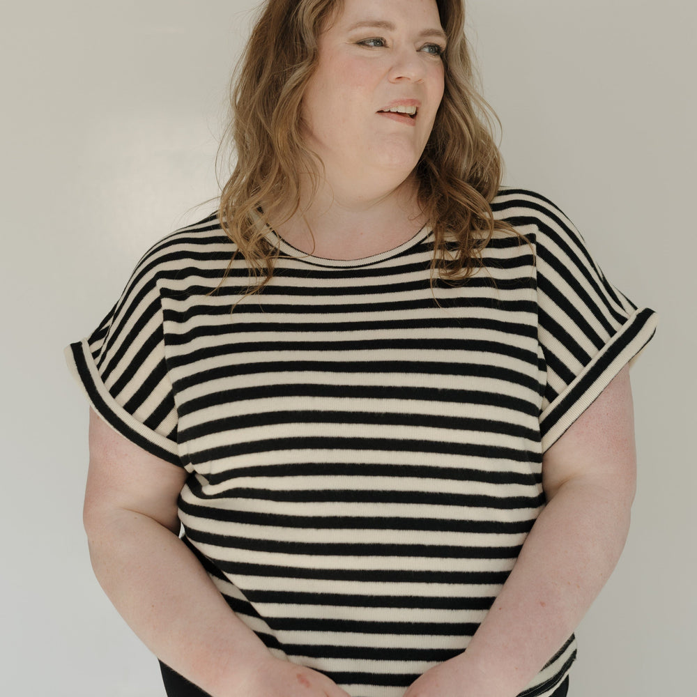 Woman wearing a black and white striped shirt against a plain background