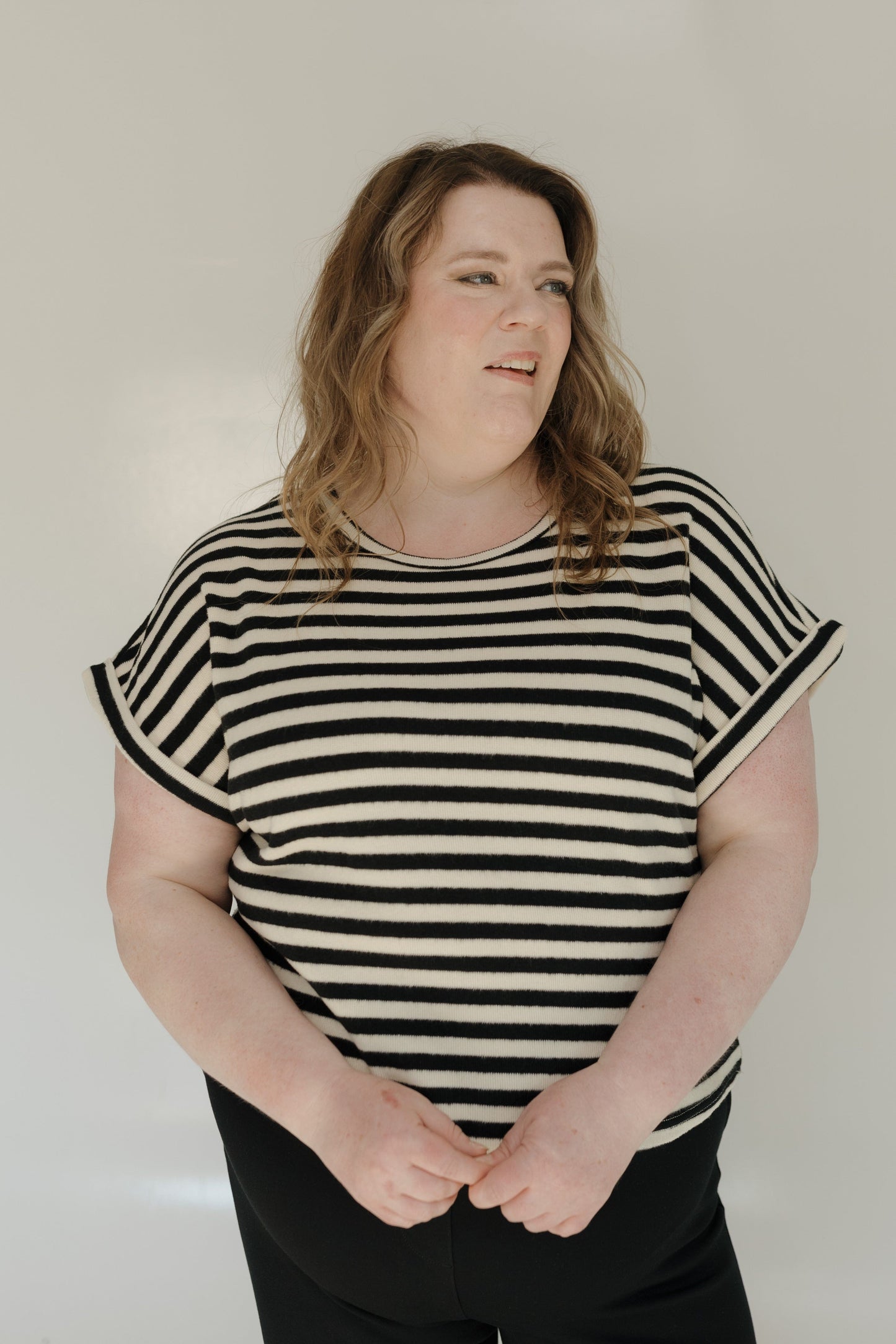 Woman wearing a black and white striped shirt against a plain background